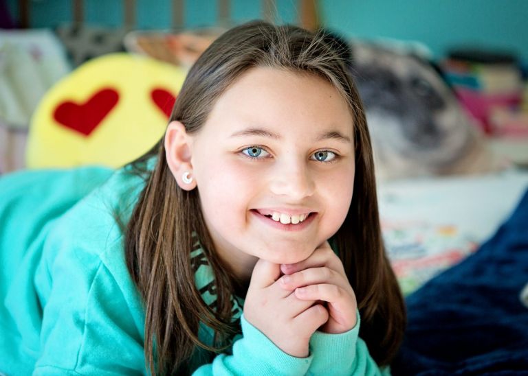 pre-teen girl smiling with colourful pillows in background