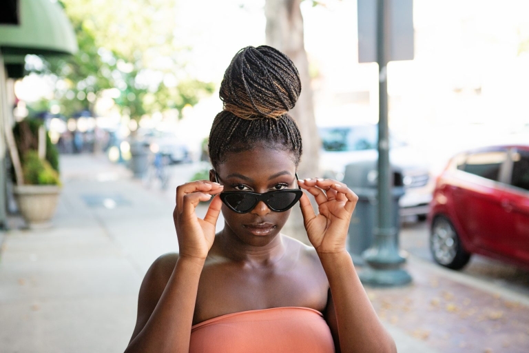teen girl putting on sunglasses standing on urban street.